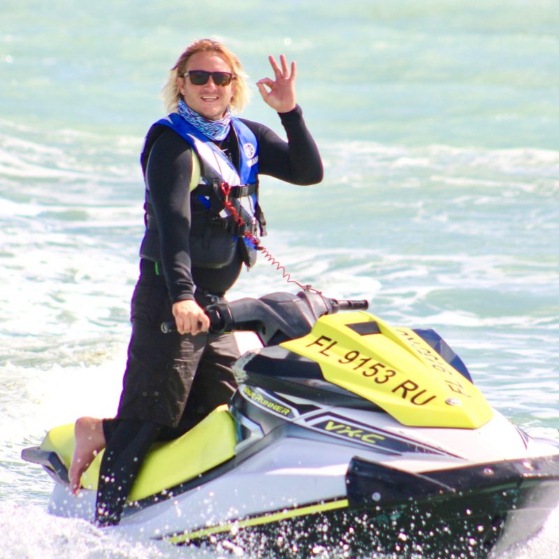 a man wearing a wet suit riding a surfboard in the water