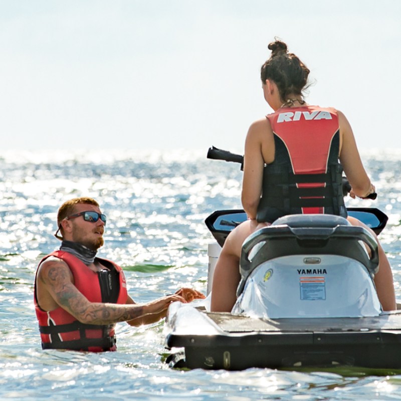 a man and woman riding on the back of a boat in the water