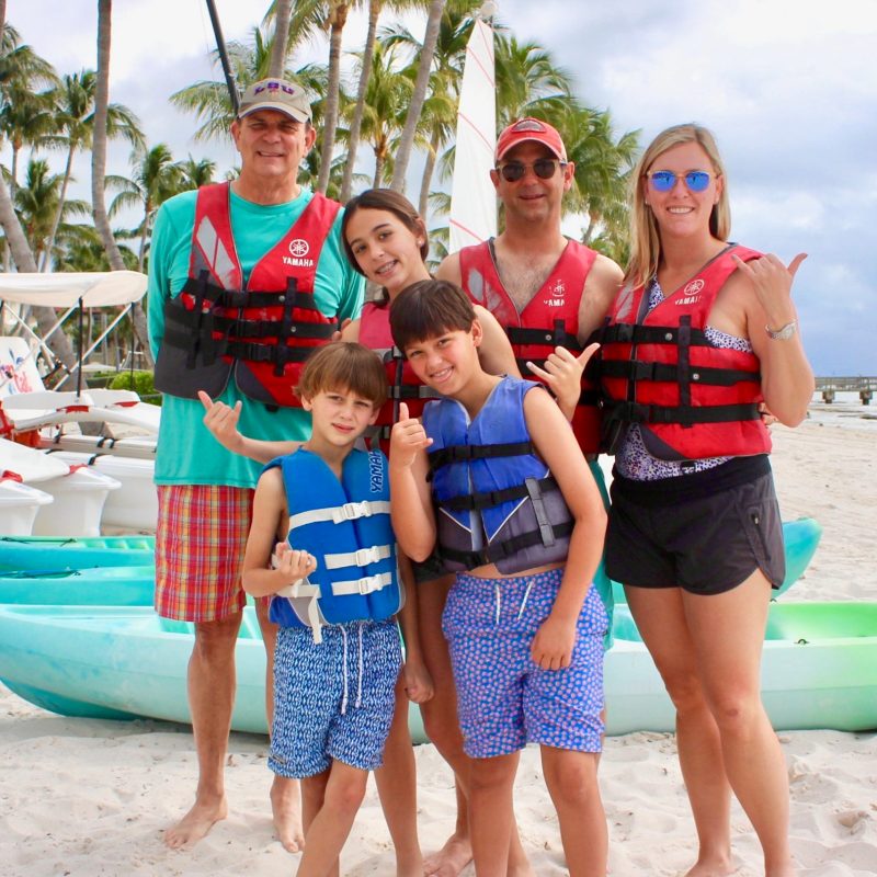 a family with young children standing on top of a sandy beach