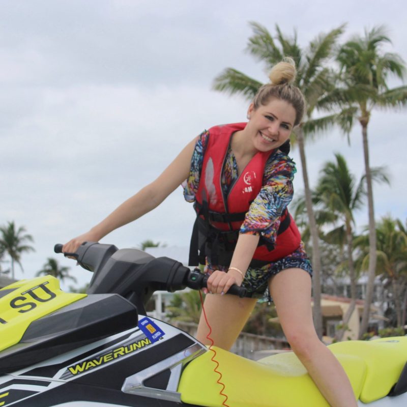 a girl standing on a jet ski posing for a picture