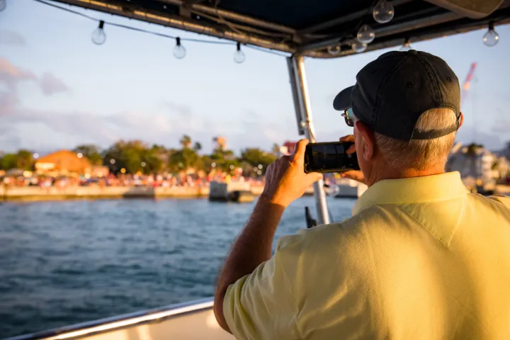 a close up of a man in a boat on the water taking a video on his phone