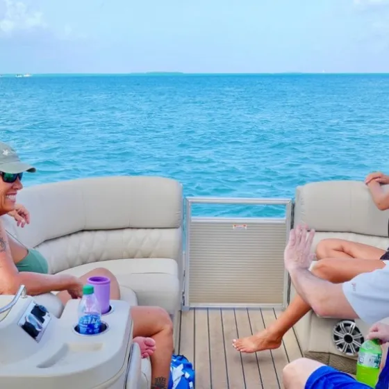 Three people relaxing on a boat in calm blue sea with clear sky.